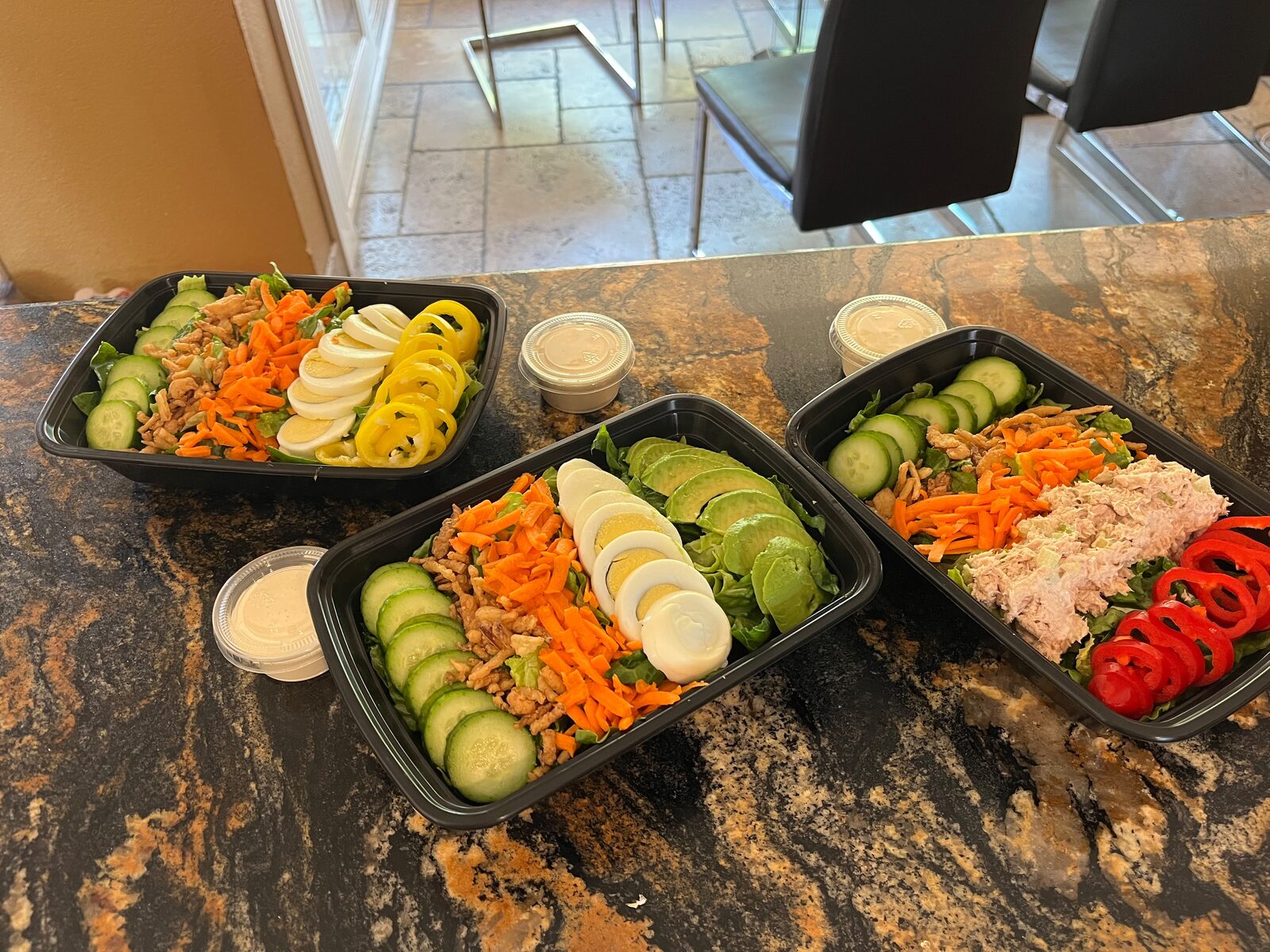 Custom salads with cucumber, carrot, egg, bell pepper, and fried onions, ready for pickup